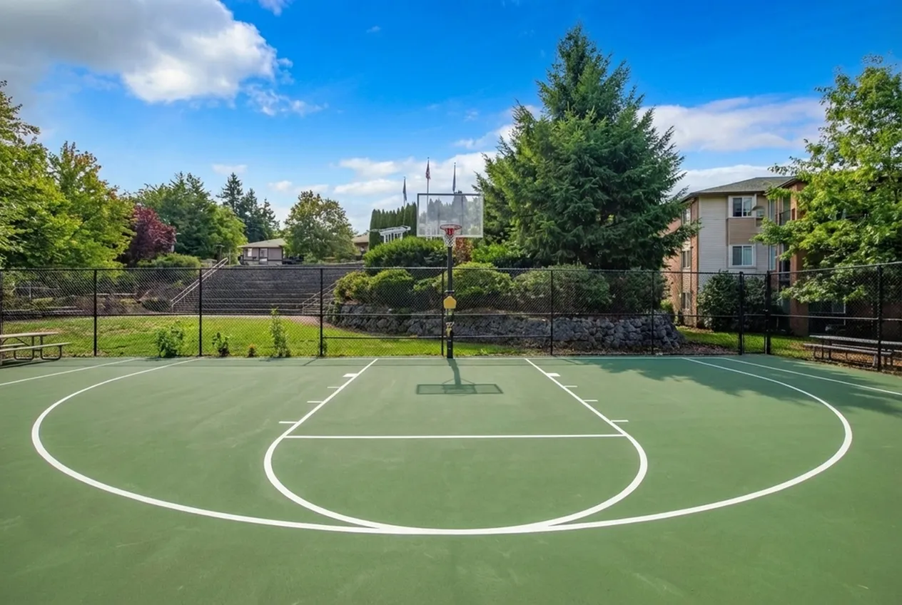 Inviting outdoor basketball court with lush greenery and vibrant blue skies, perfect for recreational activities in a serene apartment complex setting at Scott Mountain Apartments in Portland OR