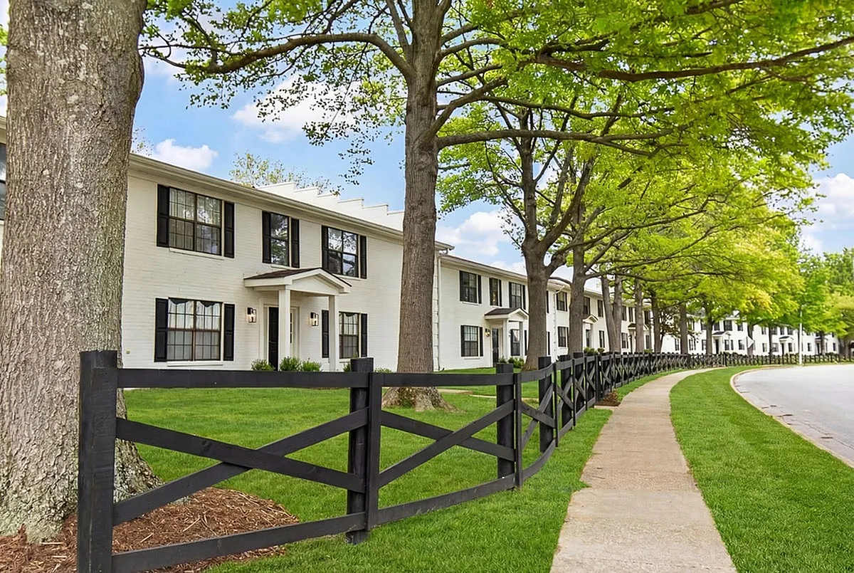 Charming Colony at the Oaks exterior with classic black and white facade, framed by lush greenery and elegant fencing, offering a serene neighborhood ambiance.