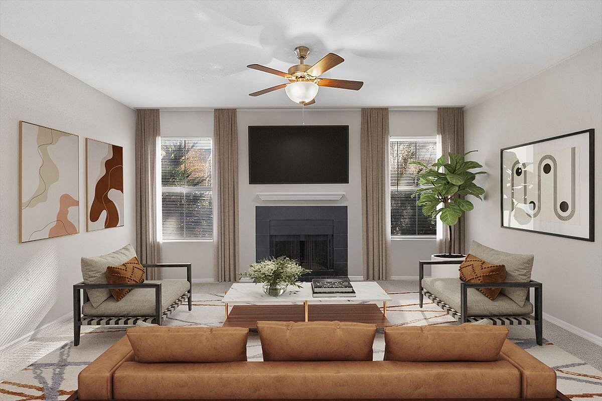 Chic living room with modern decor, featuring a cozy fireplace, elegant ceiling fan, and large windows letting in natural light  at Park at Midtown in Greensboro