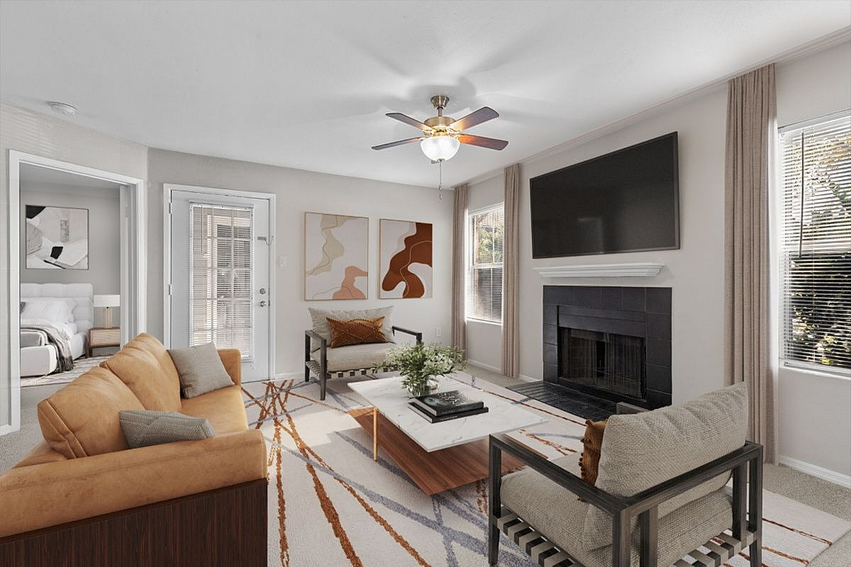 Chic living room with stylish modern furnishings, cozy fireplace, and abundant natural light, seamlessly connected to a serene bedroom  at Park at Midtown in Greensboro