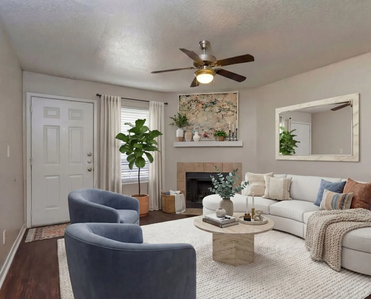 Cozy and stylish living room with a white sectional sofa, blue armchairs, modern fireplace, and elegant decor at Steepleway Downs Apartments