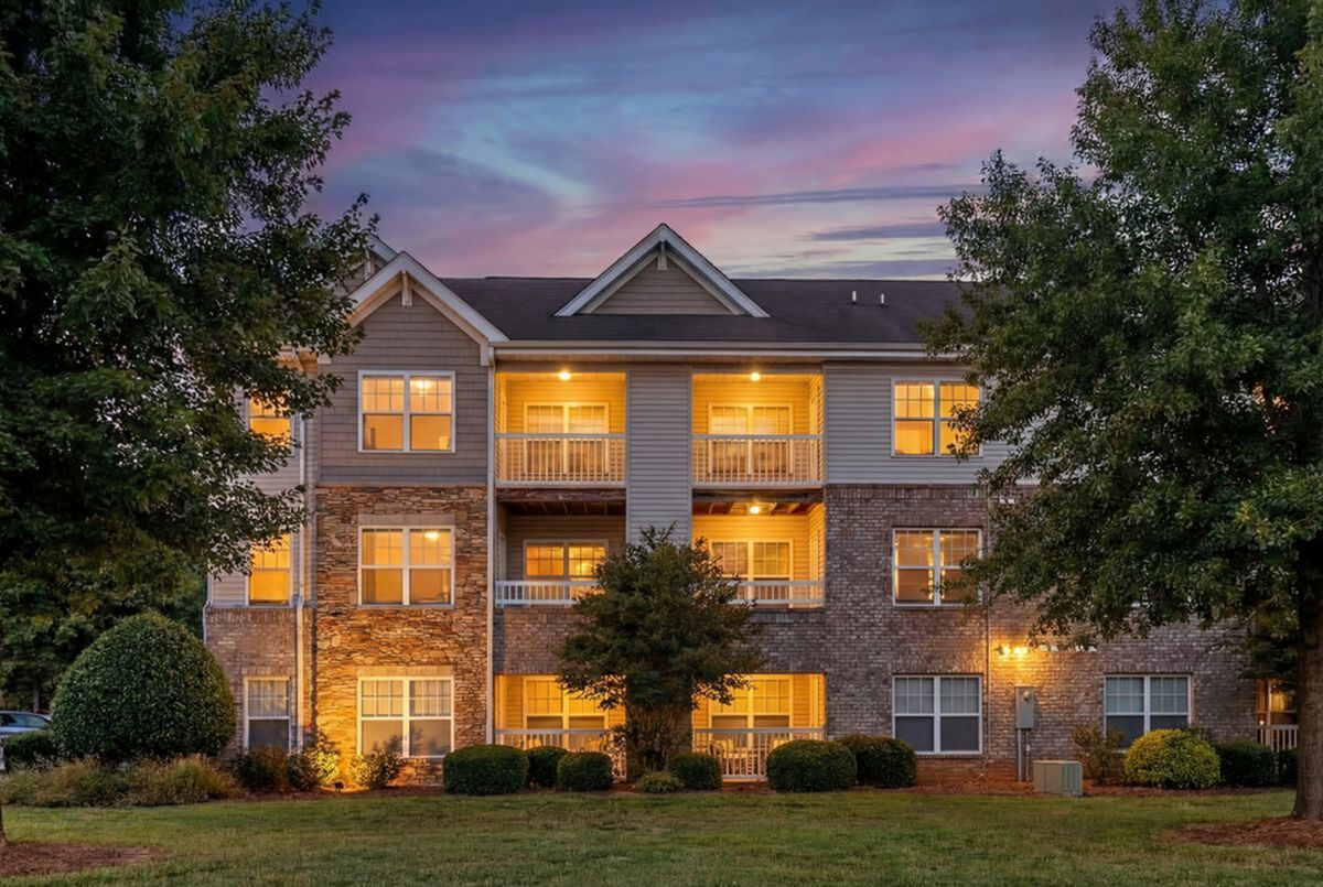 Charming apartment building with warm lighting at dusk, showcasing welcoming balconies and well-manicured landscaping at Stratford at Hillcrest Apartments
