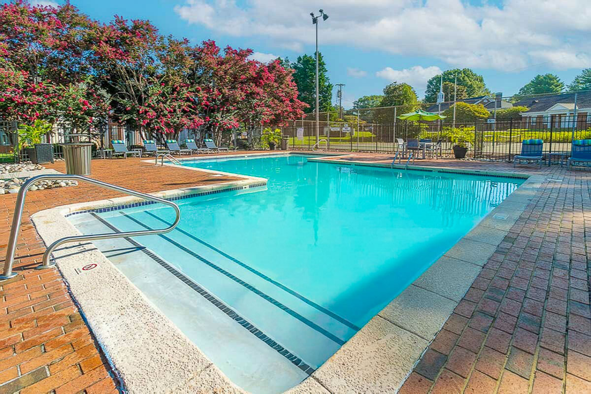 Inviting swimming pool at Park at Midtown Apartments surrounded by lush greenery and comfortable lounge chairs, perfect for relaxation.