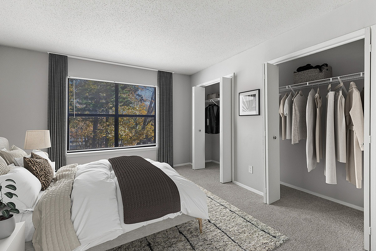 Bright and inviting bedroom with plush bedding, stylish decor, and spacious walk-in closets, complemented by a large window offering scenic views at Park at Oak Ridge.