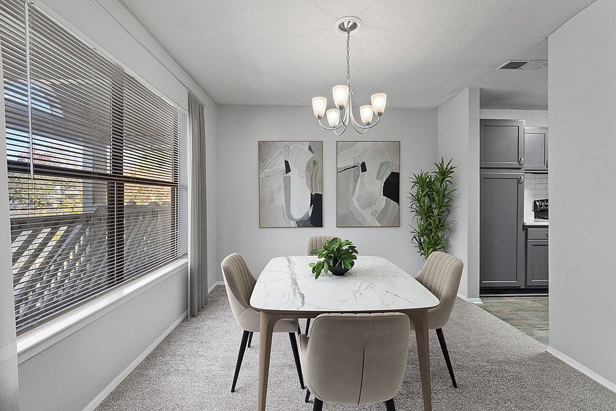 Bright dining area with a chic marble table, elegant chandelier, modern artwork, and a view into a stylish kitchen. Perfect for entertaining and family gatherings at Park at Oak Ridge Apartments.
