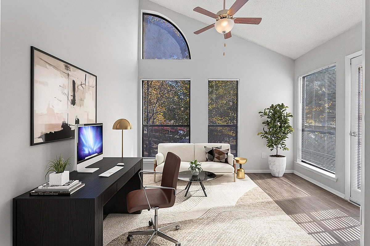 Bright and contemporary home office with sleek black desk, modern decor, and large windows offering serene outdoor views at Park at Oak Ridge Apartments.