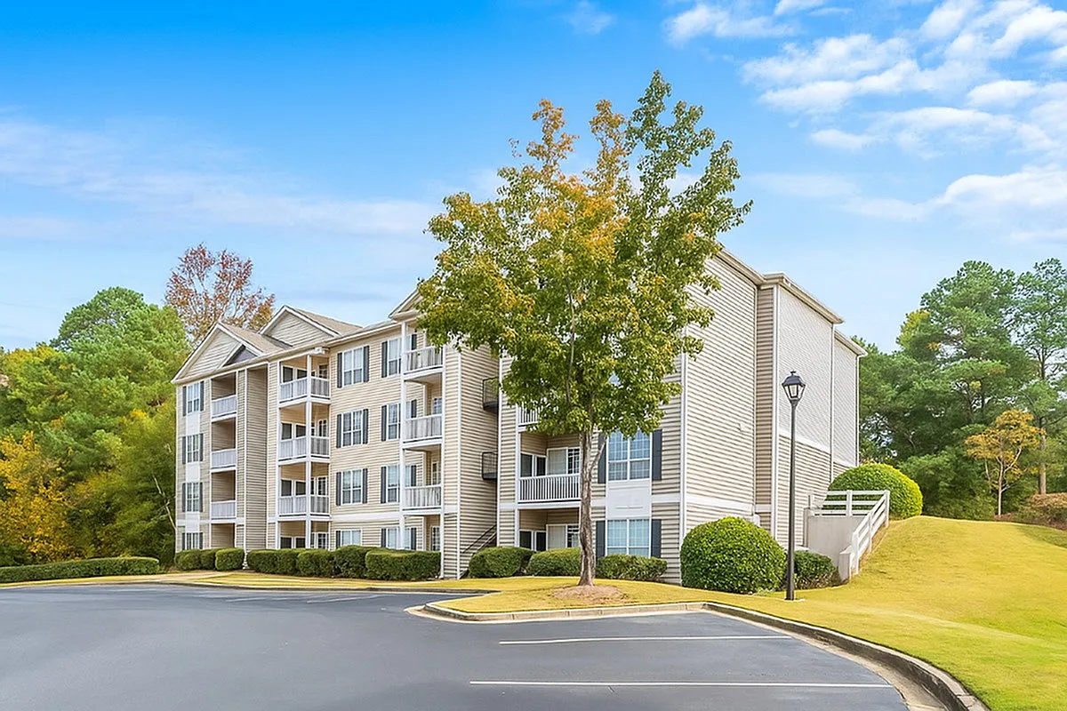 Charming apartment building with elegant balconies, nestled in lush greenery and bathed in warm sunlight at Lake St James in Conyers, GA.