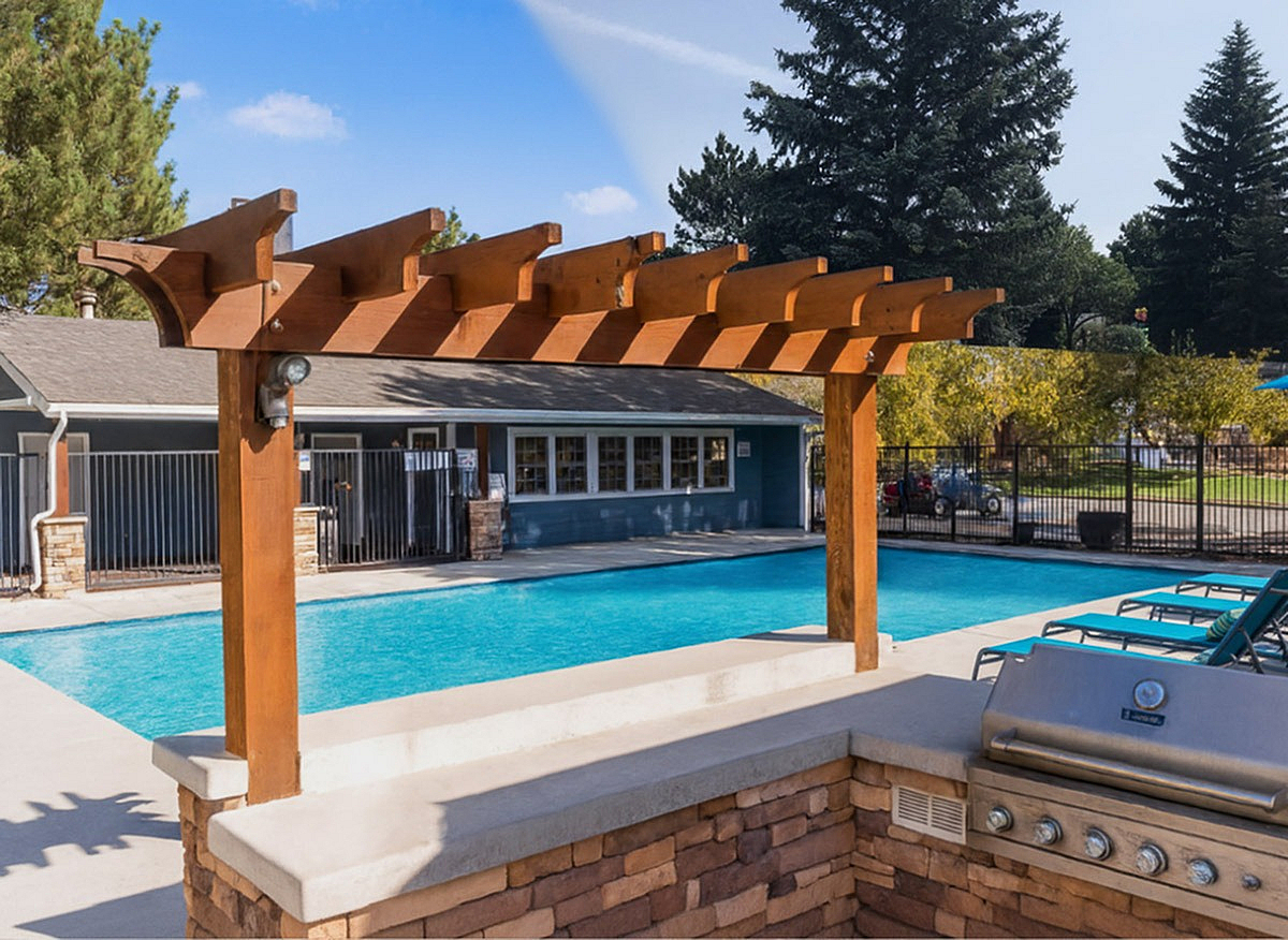 Inviting outdoor pool area at Antero Apartments with a modern pergola and built-in barbecue grill, perfect for relaxing and entertaining.