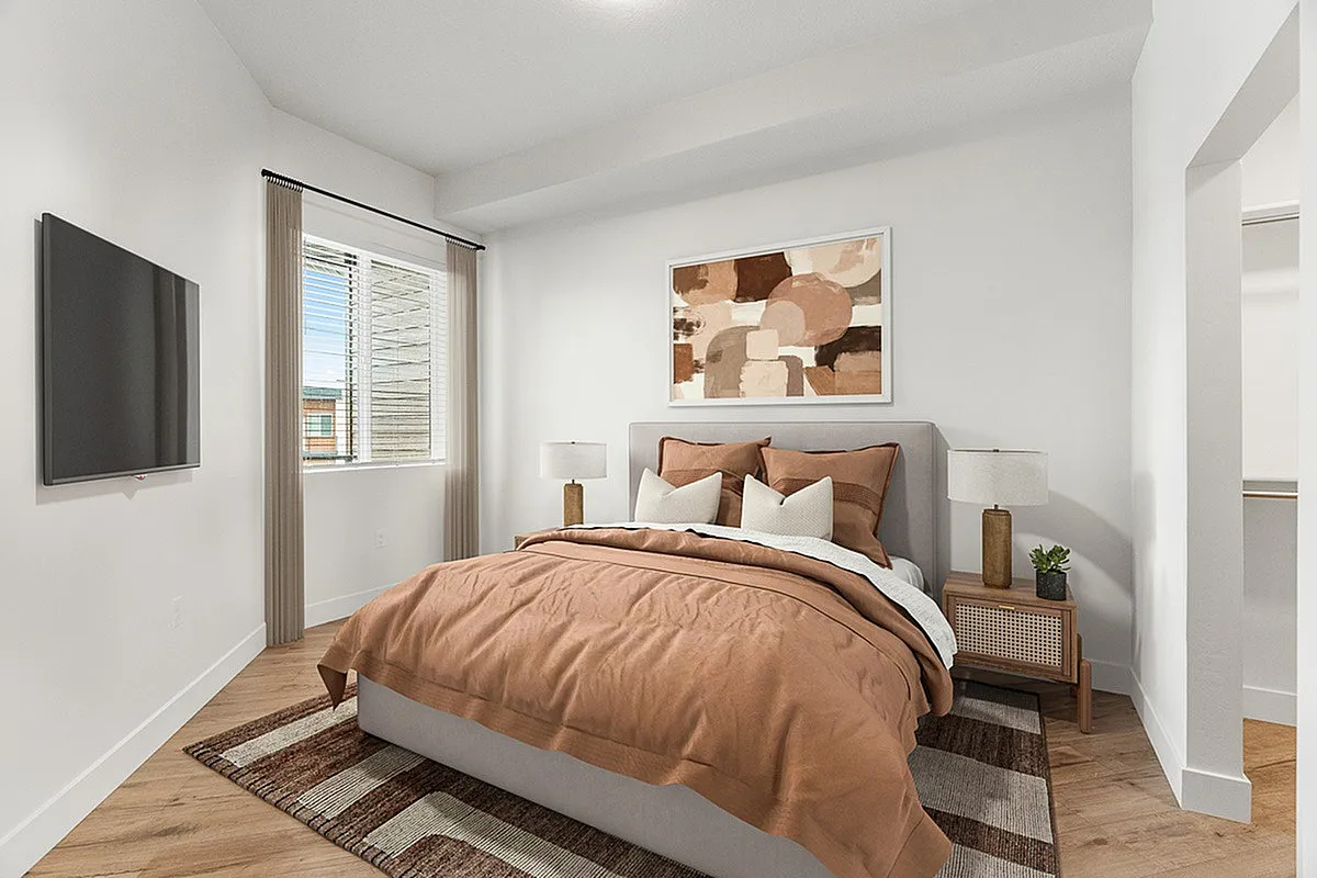 Elegant bedroom with modern decor, featuring a cozy bed with warm-toned bedding, abstract wall art, and natural light streaming through a large window, creating an inviting and serene atmosphere.