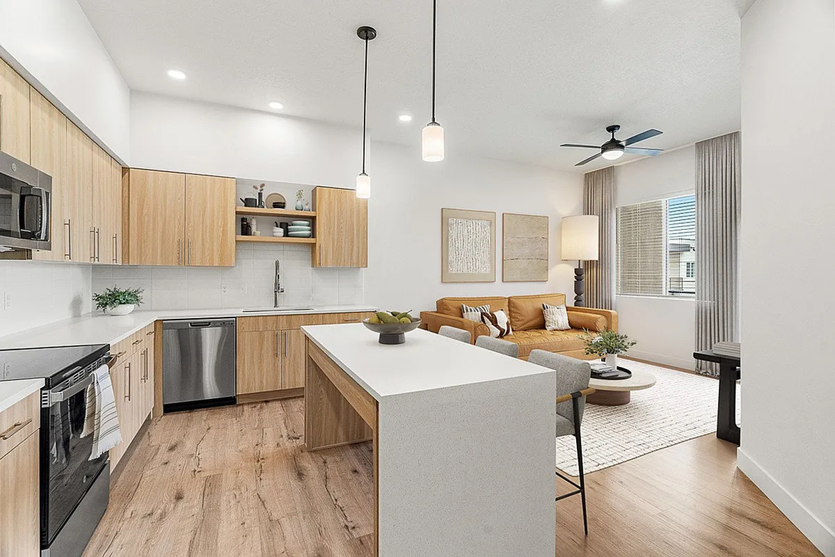 Modern open-concept kitchen and living room with natural wood cabinets, sleek countertops, and elegant decor.