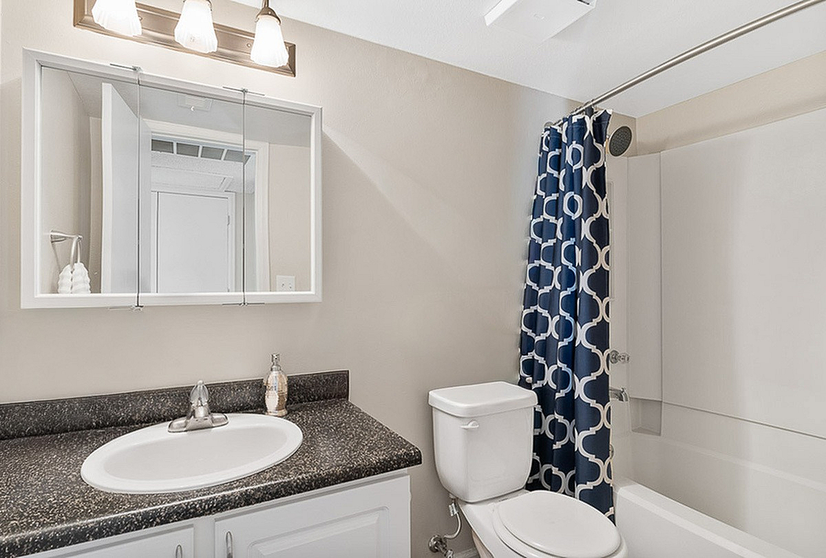 Bright, modern bathroom at Antero with elegant vanity, polished countertops, and stylish patterned shower curtain.