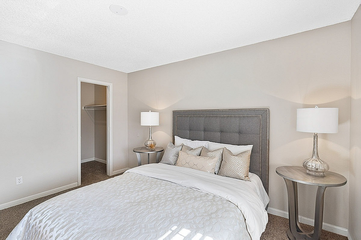 Elegant bedroom at Antero Apartments in Colorado Springs with a plush bed, stylish pillows, and modern side tables in a cozy, well-lit space.