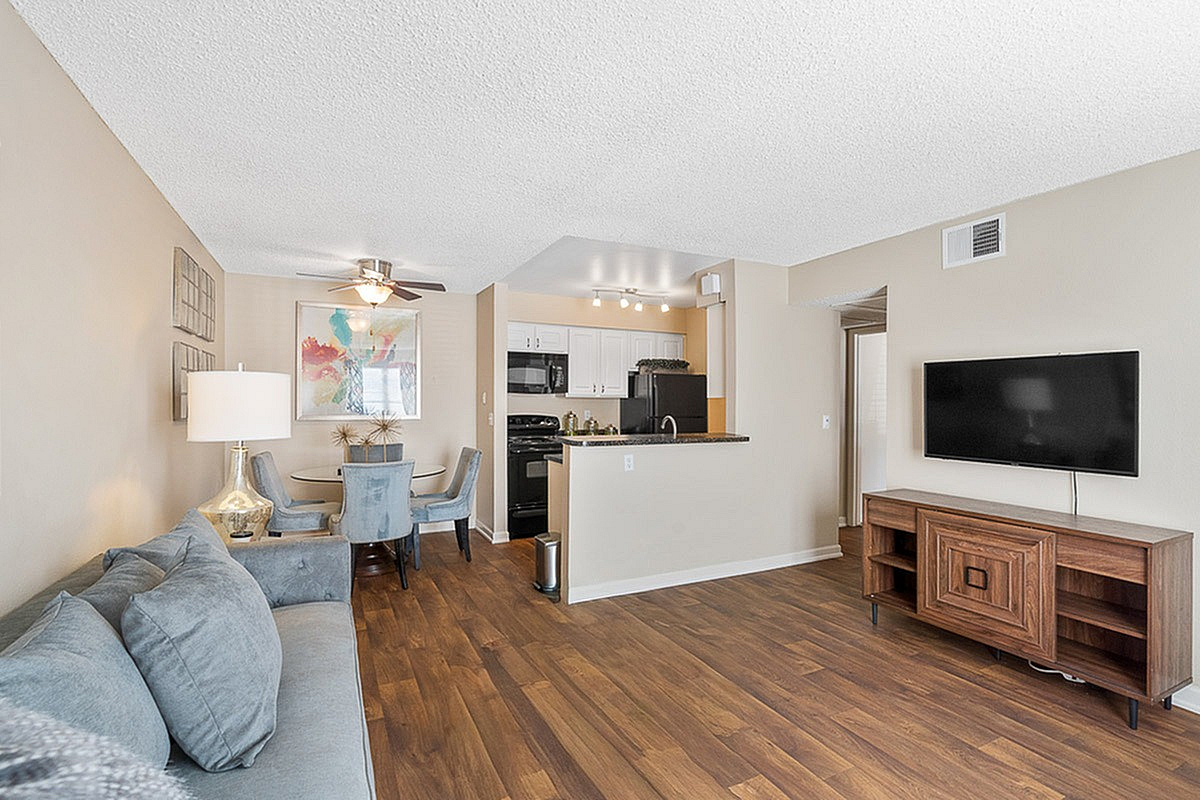 Inviting open-concept living space with elegant wooden floors, modern kitchen, and cozy dining area, perfect for stylish living at Antero Apartments.
