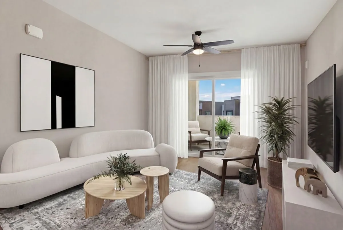 Chic living room with cozy white seating, stylish coffee tables, and large windows opening to a sunny balcony at Summit on Boulder Apartments in Henderson NV