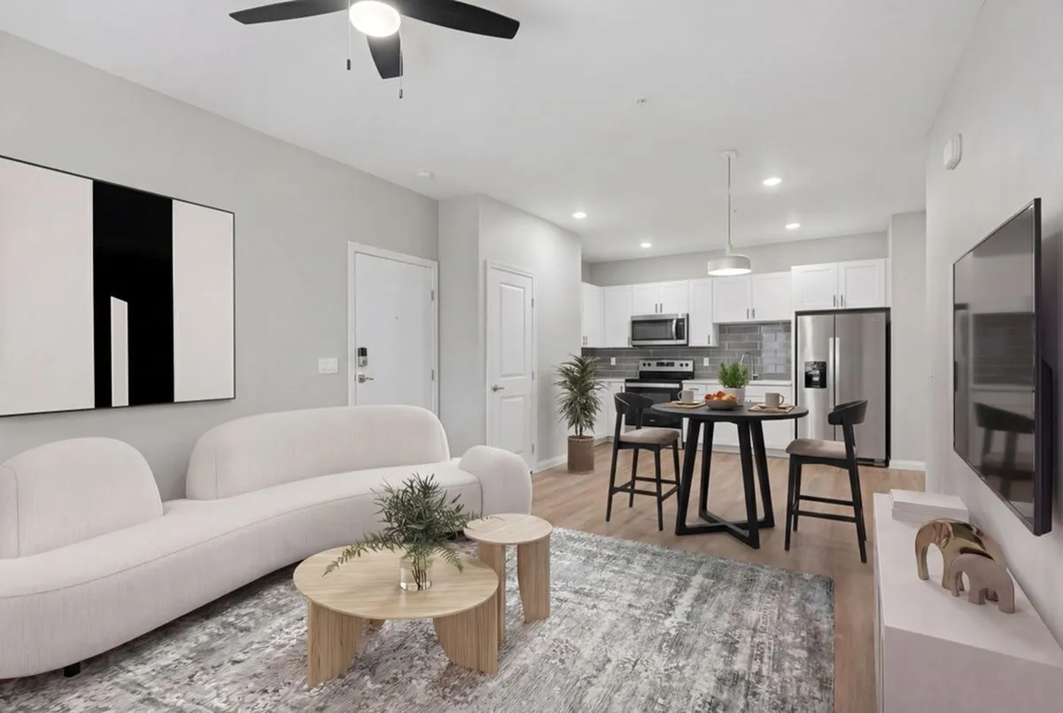 Contemporary open-plan living room and kitchen with sleek furniture, modern appliances, and elegant decor at Summit on Boulder Apartments in Henderson NV