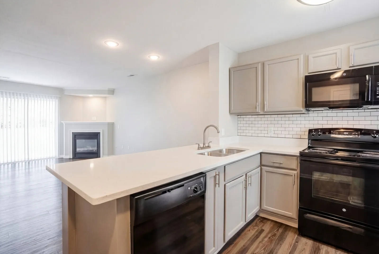 Modern open-plan kitchen with sleek countertops, stainless steel appliances, and cozy living area with fireplace.
