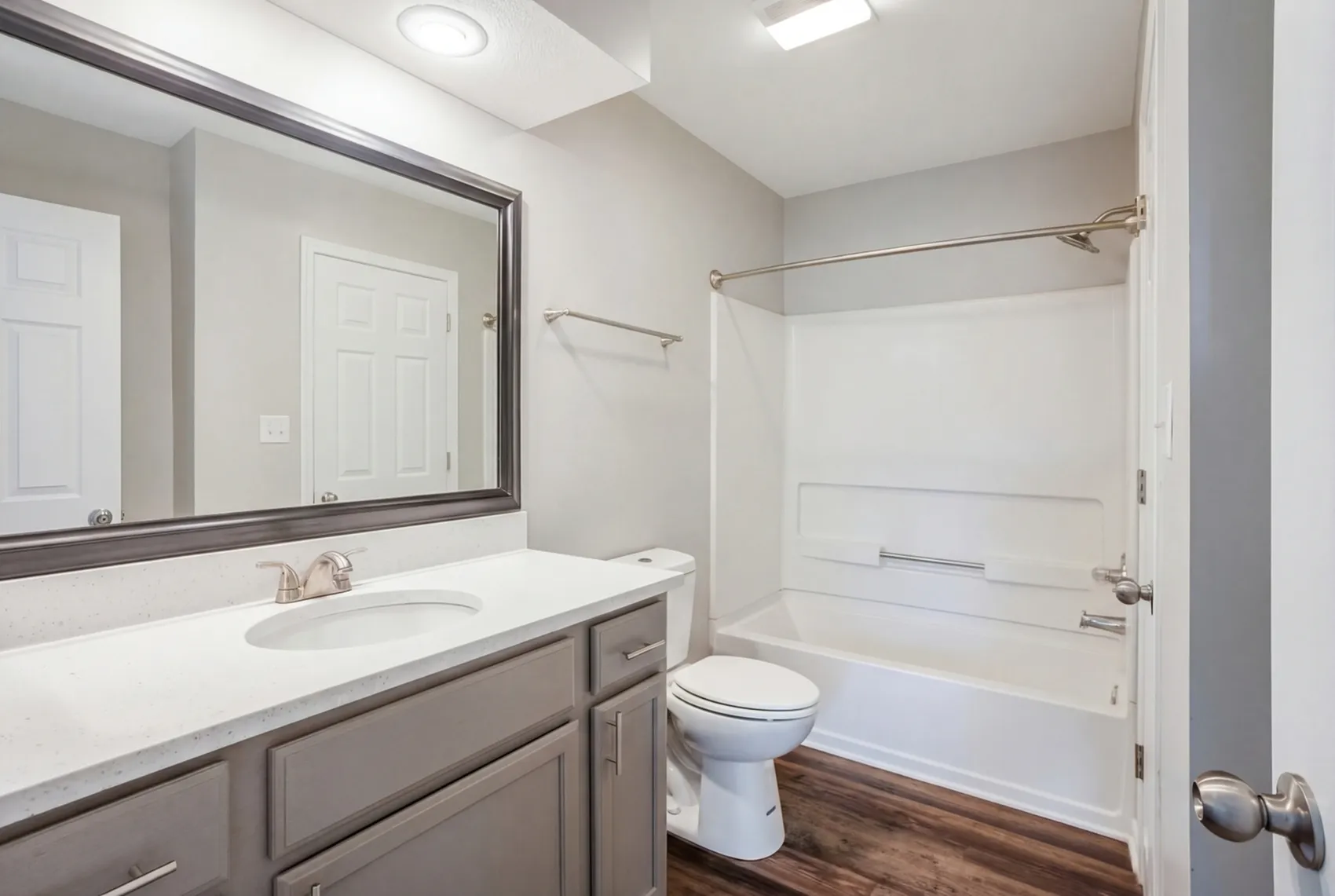 Elegant and modern bathroom featuring a sleek white vanity, large mirror, and inviting bathtub with refined finishes.