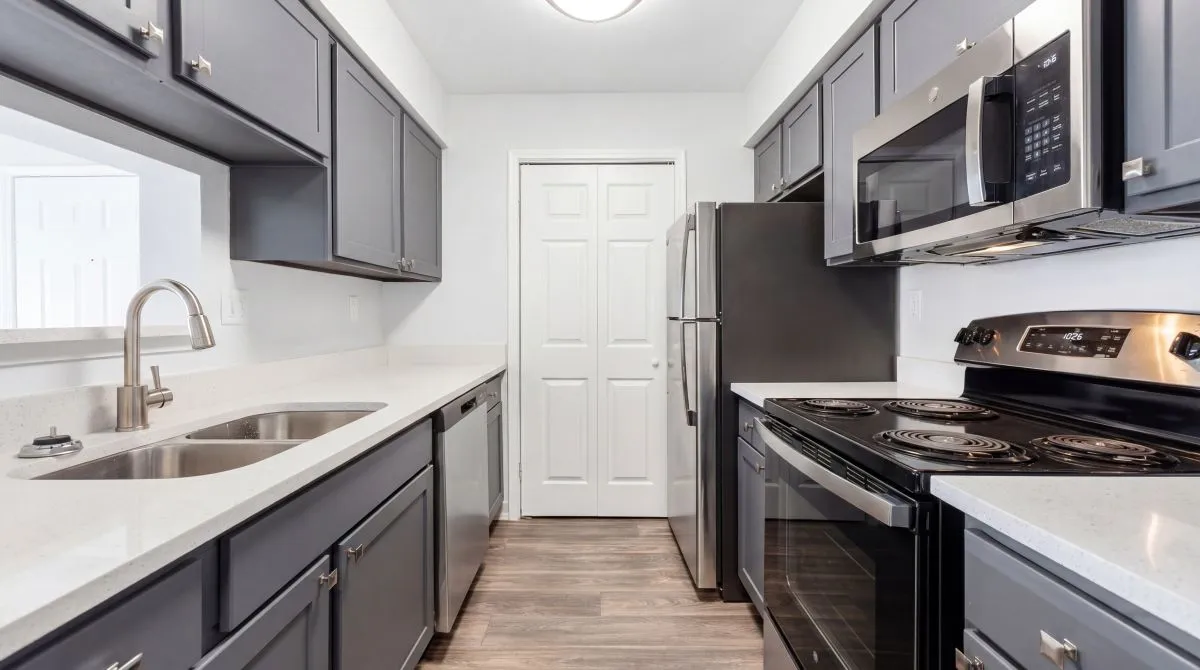 Modern kitchen with sleek gray cabinets, stainless steel appliances, and elegant countertops, offering a stylish and functional cooking space at Timber Hollow Apartments
