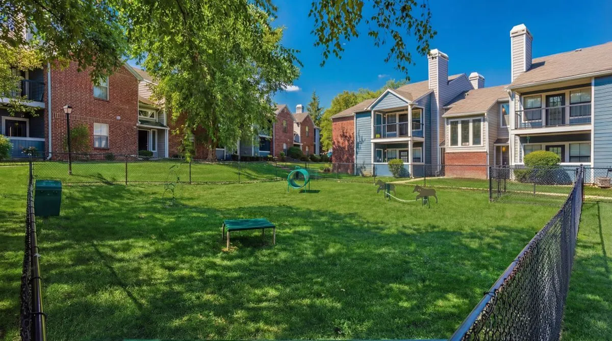 Charming apartment complex with pet-friendly green space featuring modern brick and wood facade, ideal for outdoor relaxation at Timber Hollow Apartments