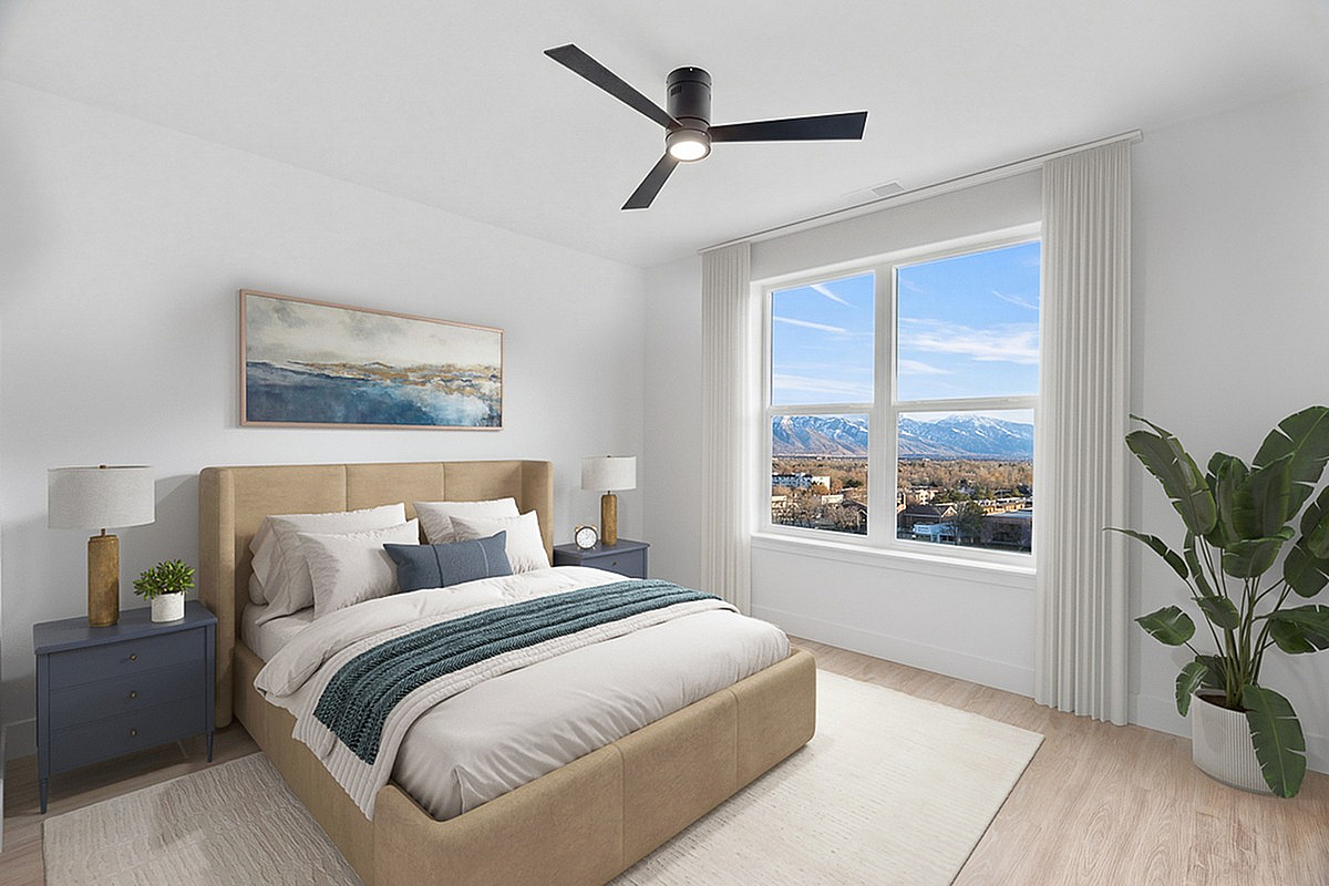 Elegant bedroom at The Westerly with mountain views through large window, featuring a cozy beige bed, modern ceiling fan, and tasteful decor.