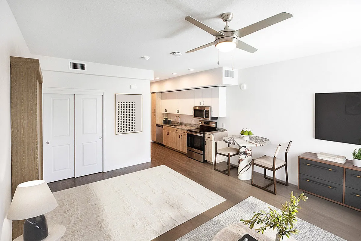 Modern open-concept living area with sleek kitchen, elegant marble dining table, and cozy lounge space with chic decor.
