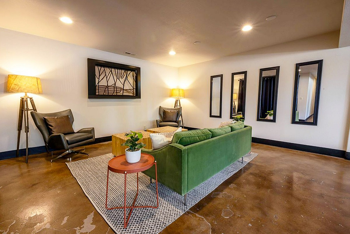 Modern clubhouse with a plush green sofa, accent chairs, stylish lamps, and contemporary artwork, ideal for a cozy and inviting atmosphere.