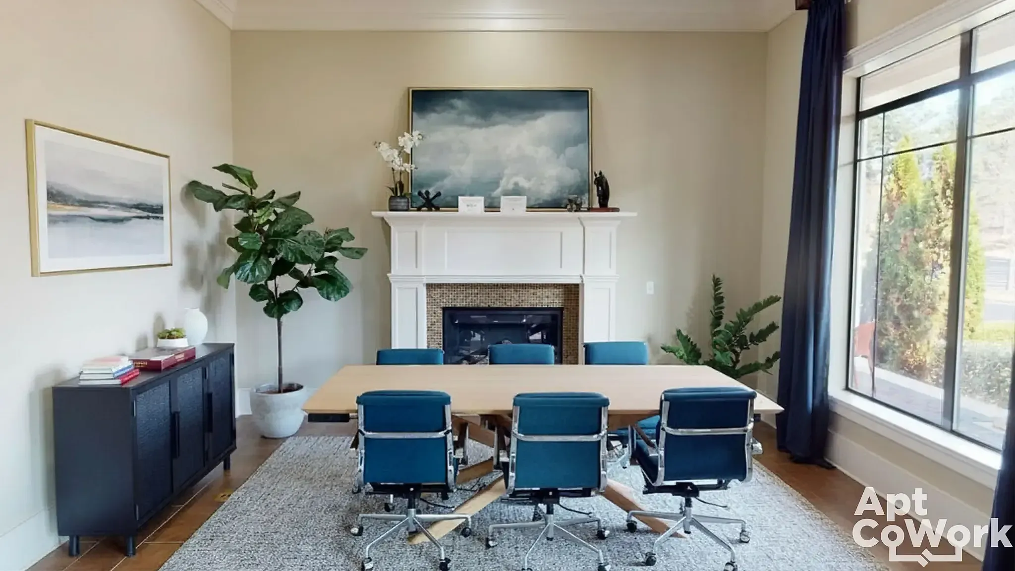 Elegant meeting room at Heights at Meridian Apartments with stylish blue chairs, polished wooden table, and a cozy fireplace under a serene cloud painting.