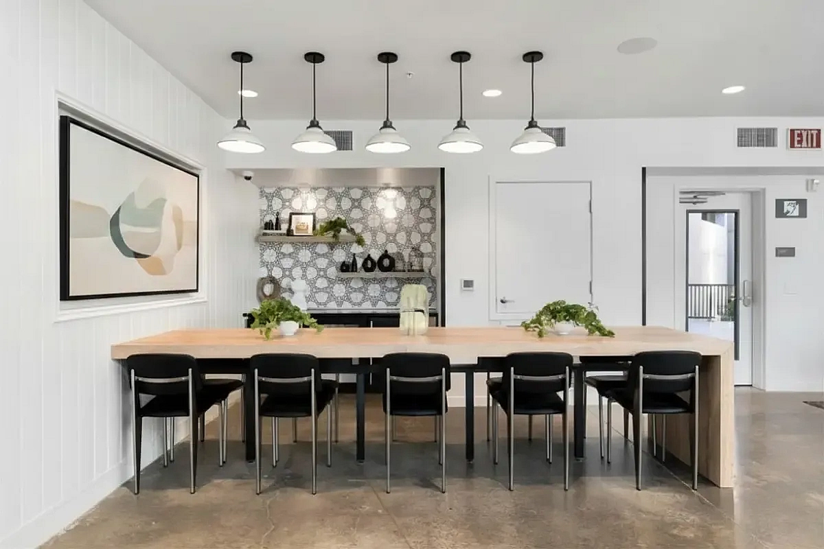 Modern dining space with long wooden table, black chairs, and elegant pendant lighting at 805 Riverfront Apartments in Sacramento