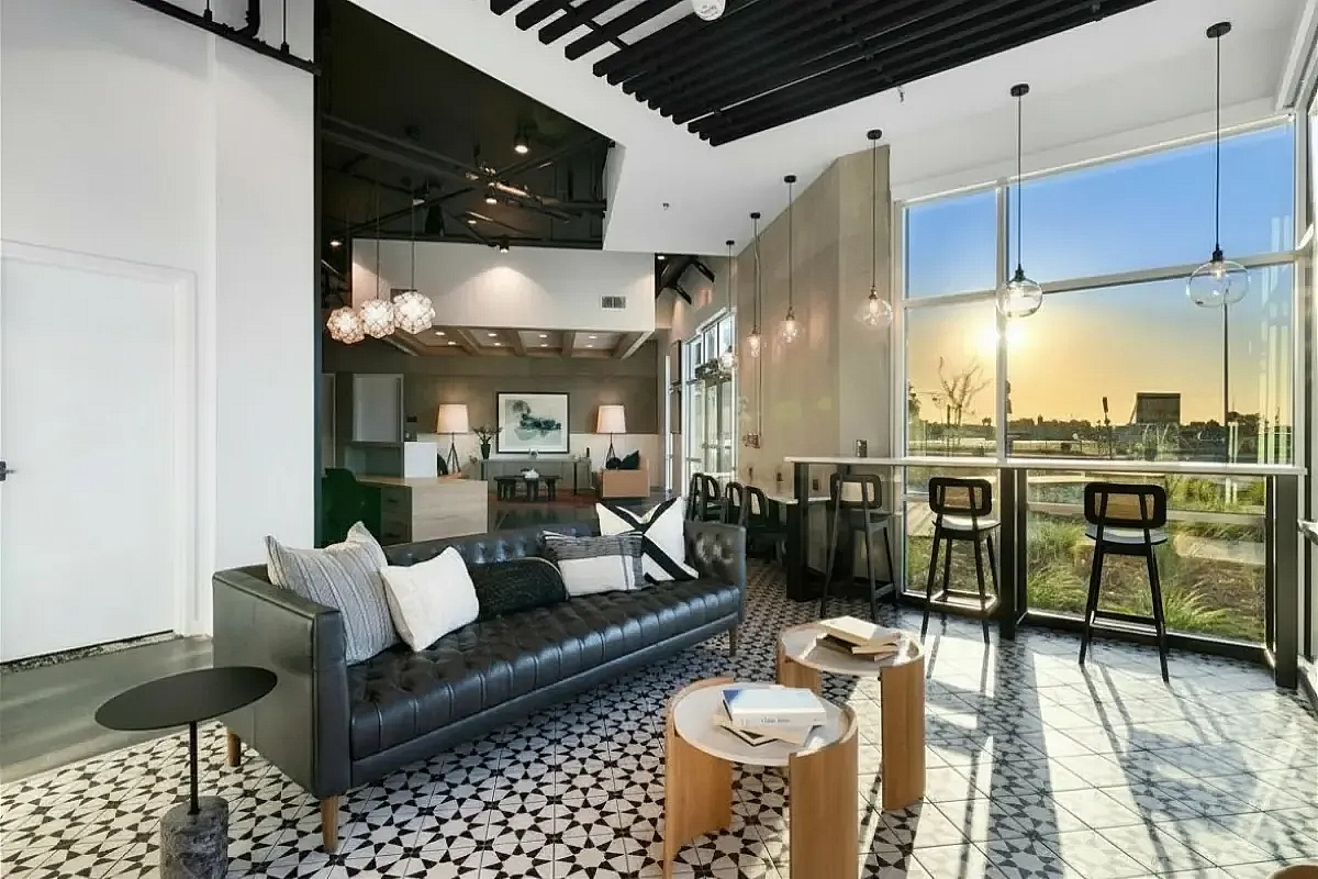 Clubroom with modern furnishings, stylish lighting, and expansive windows offering a panoramic sunset view at 805 Riverfront Apartments in West Sacramento