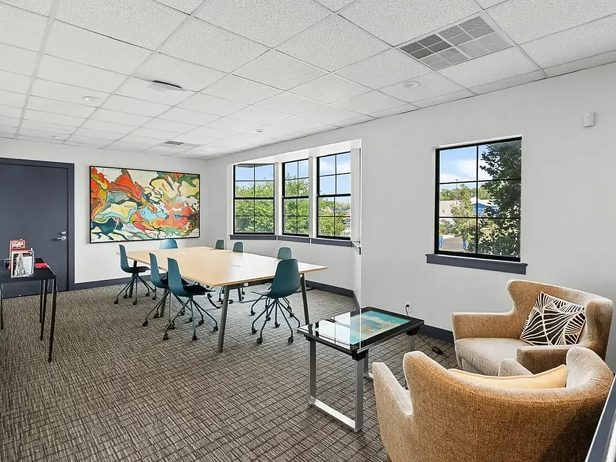 Modern meeting room with stylish chairs, vibrant artwork, and large windows presenting a bright, inviting atmosphere  at Apt CoWork at Cottonwood Apartments in Salt Lake City