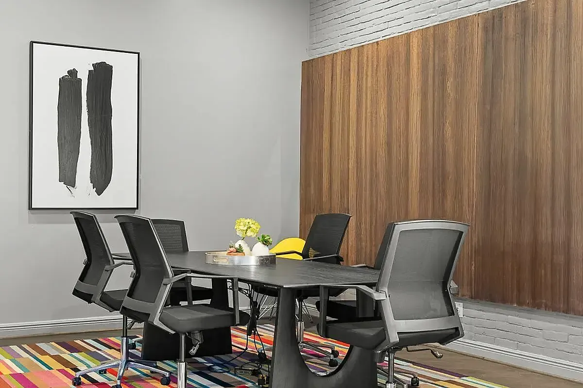Contemporary meeting room with sleek black office chairs, a stylish table, vibrant striped rug, and modern artwork at Apt CoWork in Charlotte, NC