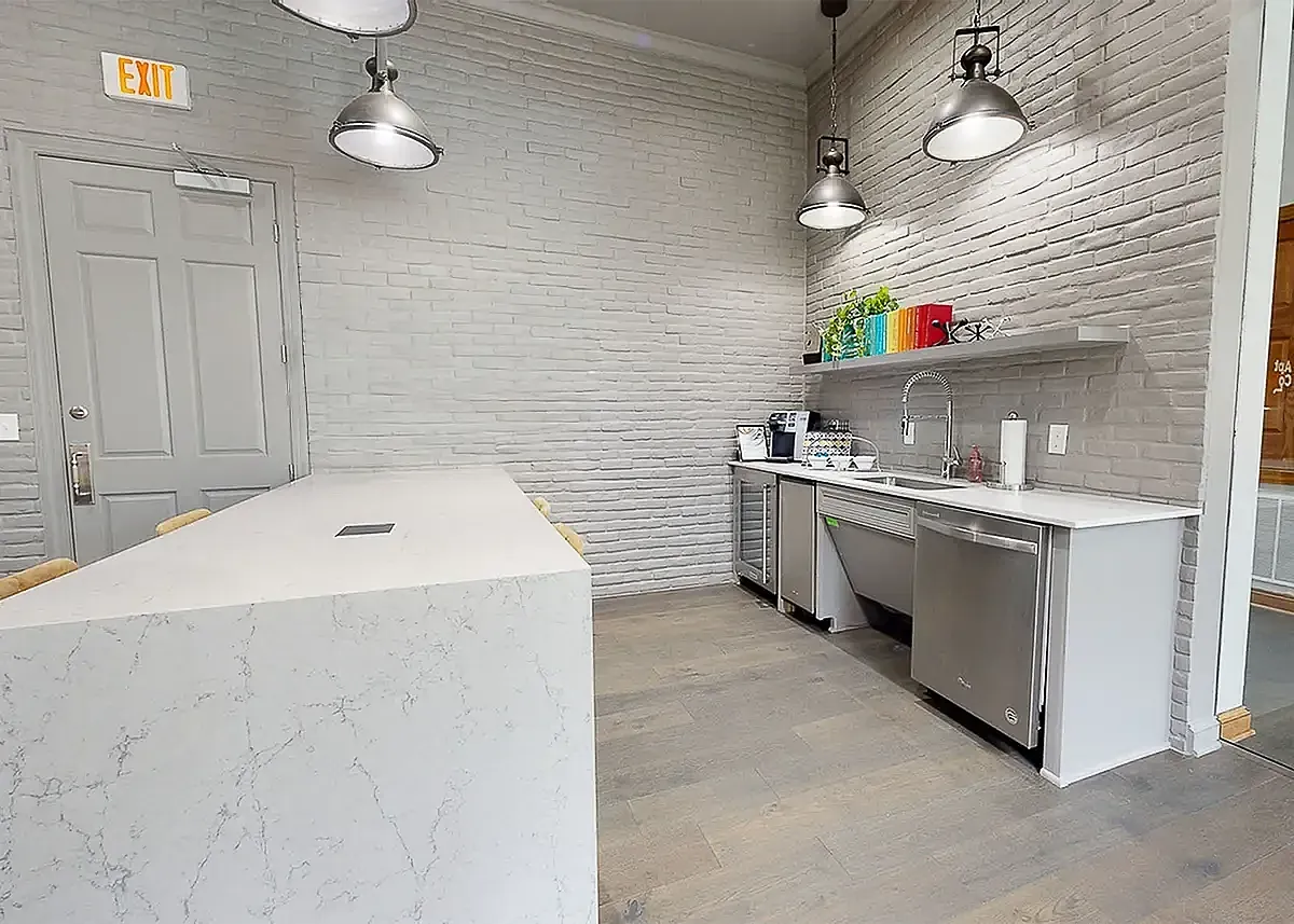 Chic modern kitchen with a sleek marble island, industrial lighting, and stylish brick walls at Cottonwood Ridgeview.
