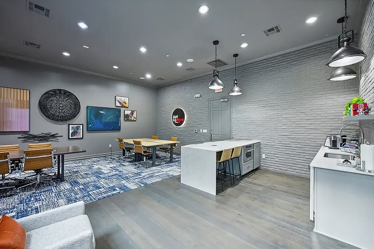 Modern coworking space at Cottonwood Ridgeview Apartments featuring sleek tables, contemporary art, and a stylish kitchen area with bar seating.