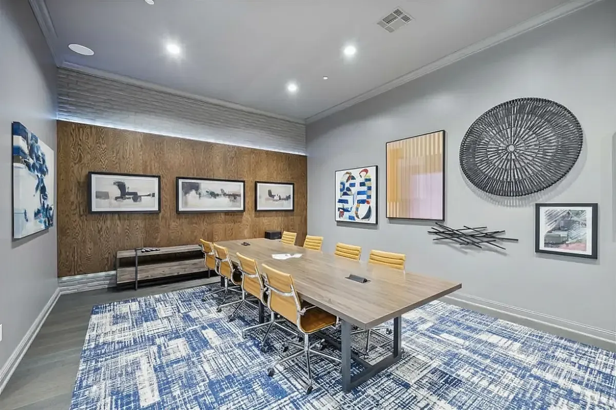 Modern conference room at Cottonwood Ridgeview Apartments with a sleek wooden table, stylish yellow chairs, and vibrant artwork on the walls, creating an inspiring workspace atmosphere.