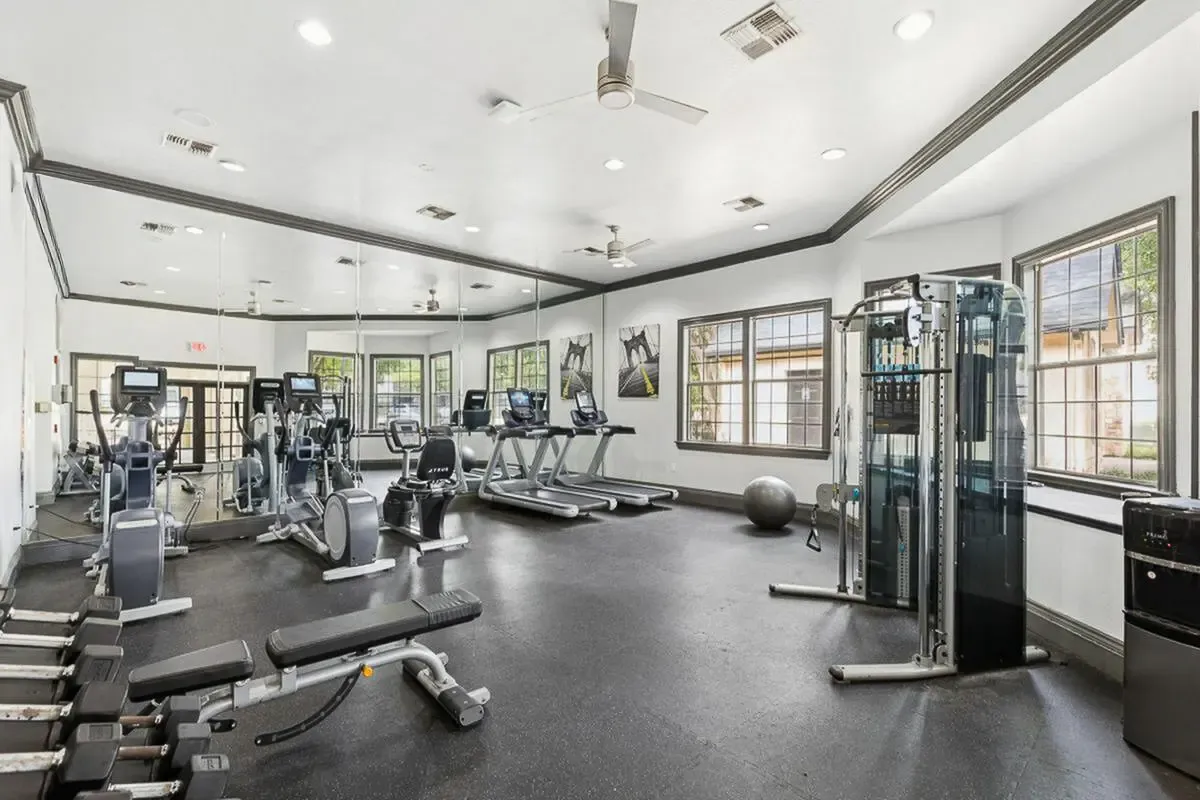 Bright and modern fitness center equipped with state-of-the-art exercise machines, large mirrors, and natural lighting Stonebriar at Frisco Apartments