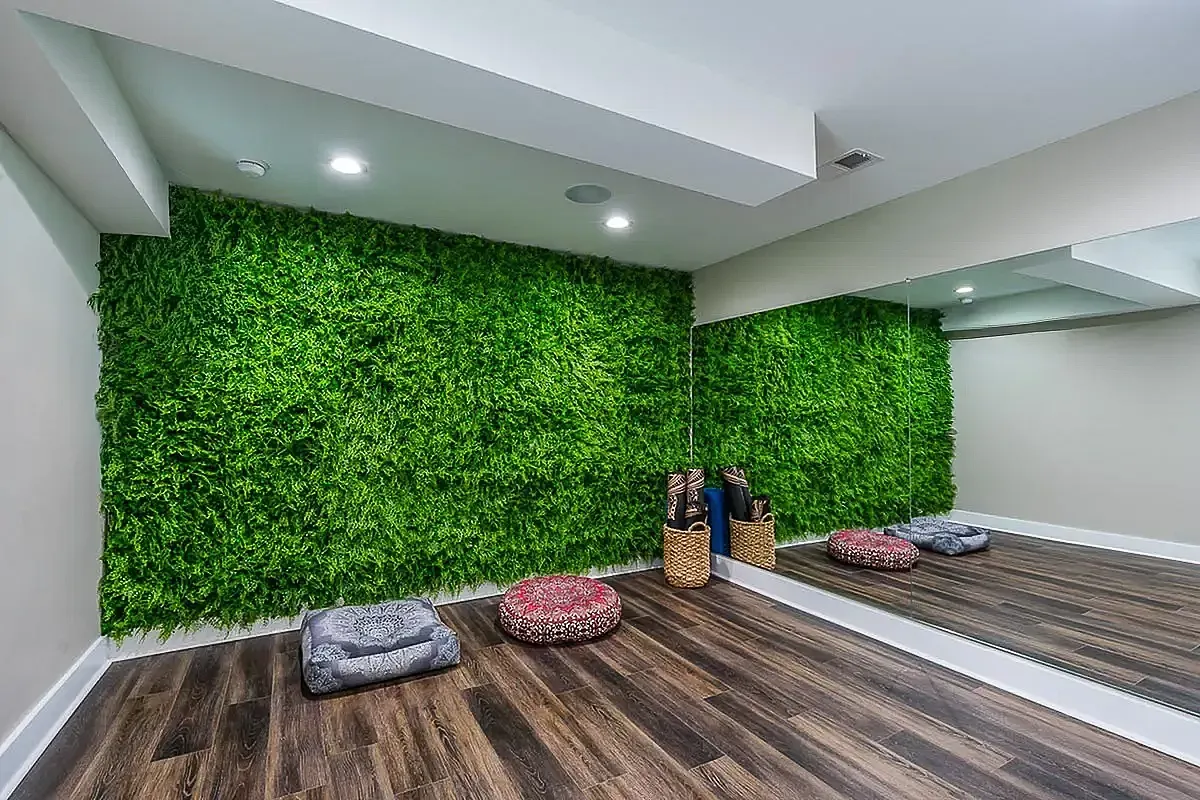 Serene yoga and meditation room at The Colony at the Oaks Apartments with vibrant green moss wall, soft cushions, yoga mats, and calming nature video.
