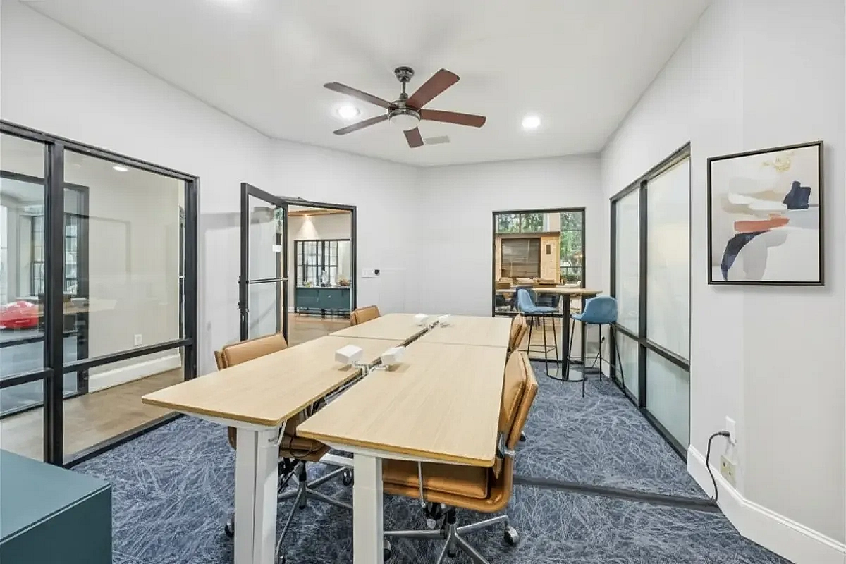 Modern conference room space with sleek glass partitions, adjustable desks, and stylish seating, perfect for dynamic work environments at Apt CoWork at Toscana at Valley Ridge Apartments in Lewisville Texas