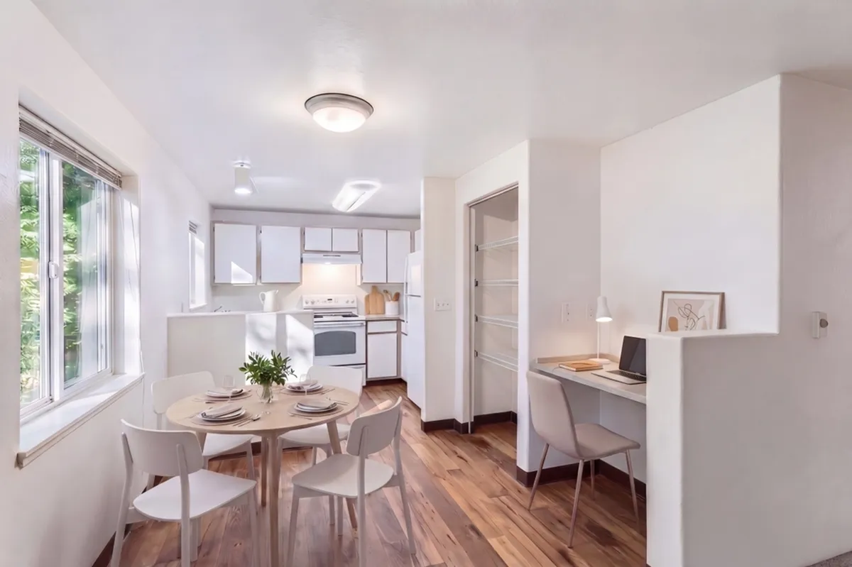 Bright, airy kitchen and dining area with sleek modern design, elegant wood flooring, and a cozy workspace.