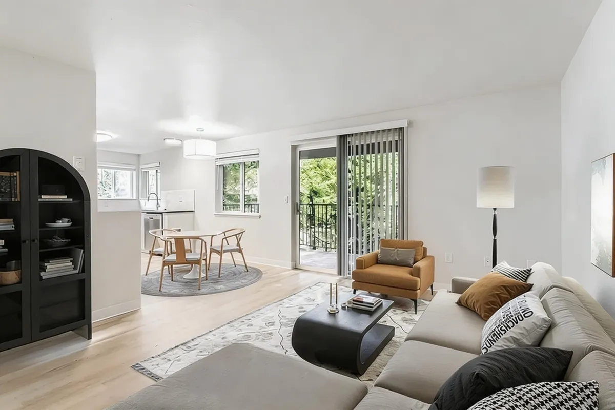 Bright open-plan living space featuring a cozy lounge area, modern dining set, and floor-to-ceiling windows leading to a balcony with lush views.