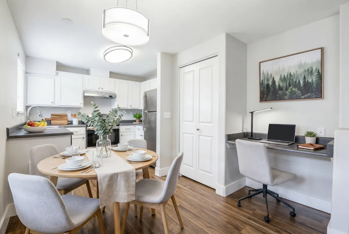 Bright, modern kitchen and dining area with elegant white cabinetry, stainless steel appliances, and a cozy work nook, perfect for home living.