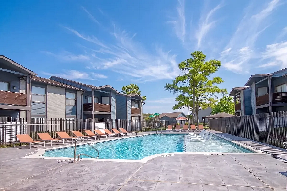 Charming apartment complex with a serene pool area and modern loungers, surrounded by lush greenery and spacious balconies at Steepleway Downs Apartments.