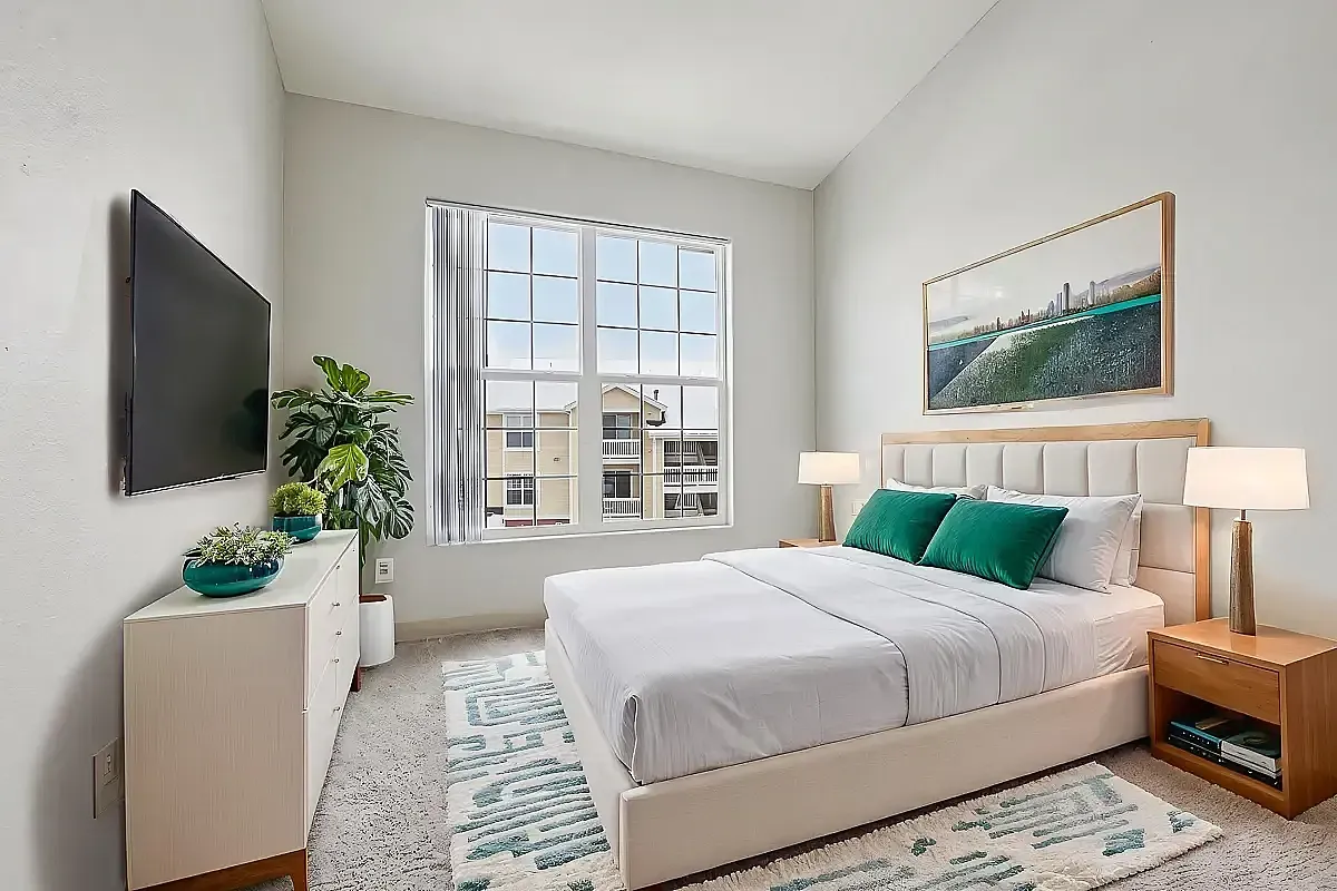 Bright, modern bedroom with large window, stylish decor, and cozy bed, filled with natural light and vibrant green accents.