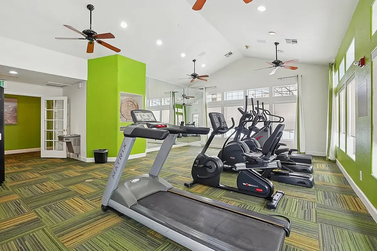 Bright and modern fitness center with treadmills and ellipticals, featuring vibrant green accents and abundant natural light.