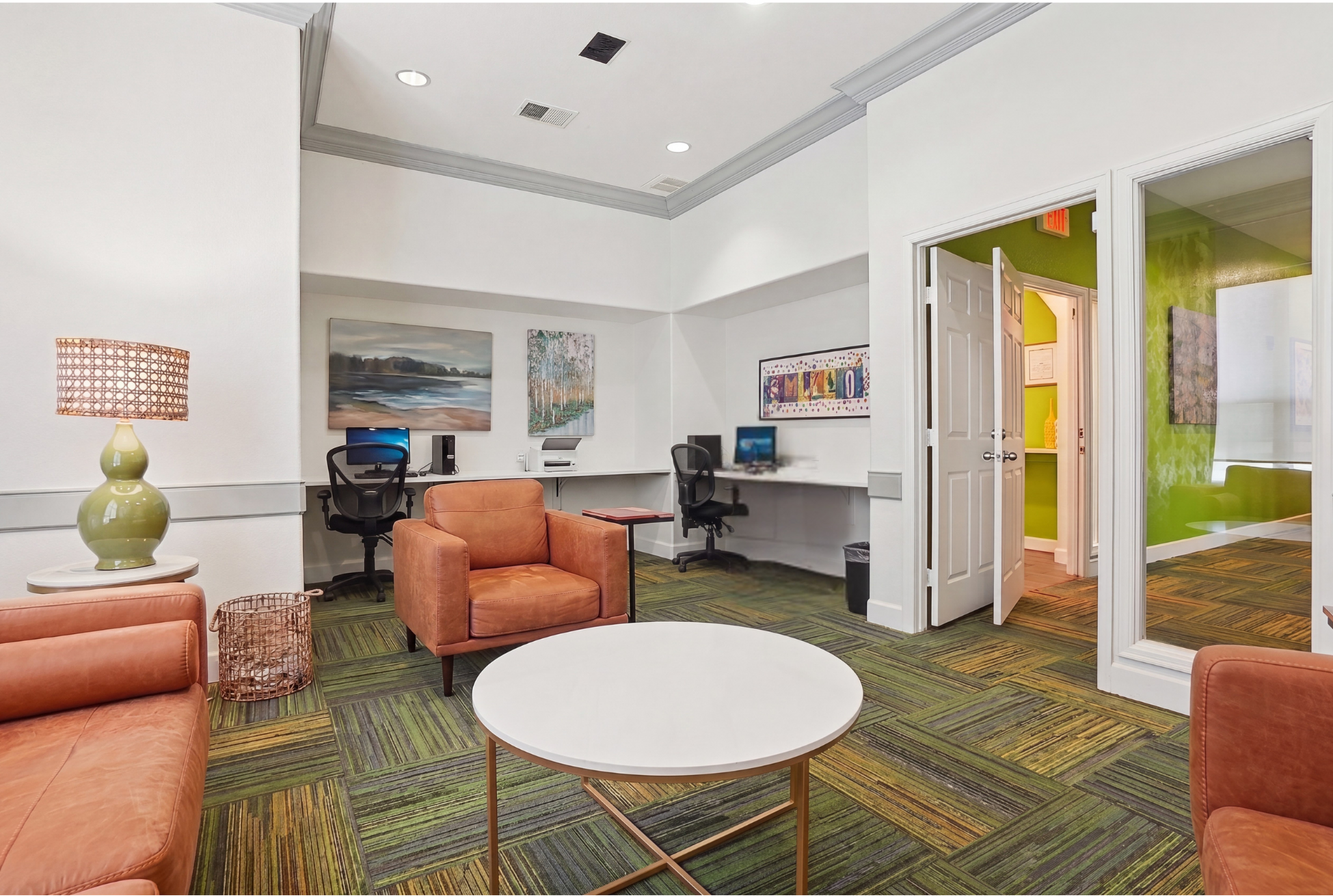 Inviting office space featuring modern decor, plush leather seating, vibrant carpet, and functional workspace with computers.