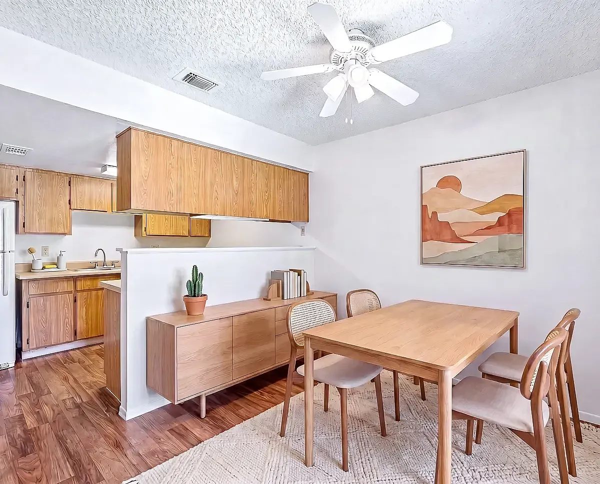 Bright dining area with wood finishes, open kitchen, and modern art on the wall for a touch of elegance.
