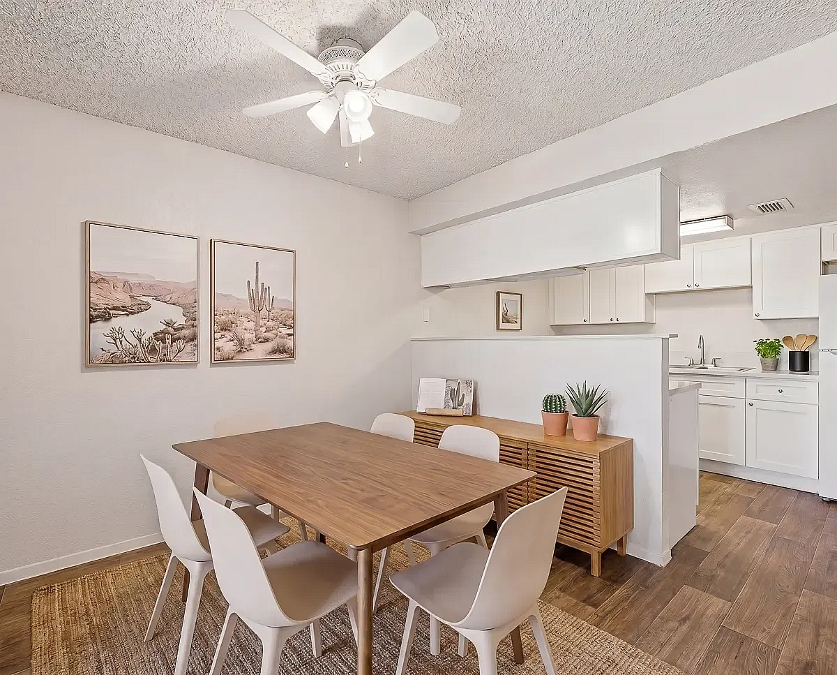 Inviting dining area with a wooden table and modern chairs, complemented by a stylish kitchen and natural decor accents.