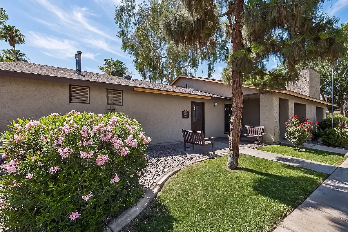 Charming exterior of laundry care center surrounded by lush greenery and vibrant flowers, offering a serene and welcoming entrance.
