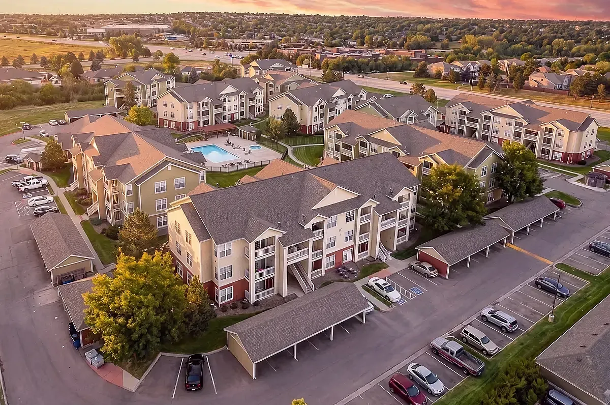 Scenic aerial view of a vibrant residential community with modern apartment buildings, lush greenery, and a sparkling pool, showcasing serene and upscale living in Centennial at The Orchards at Cherry Creek Park Apartments.
