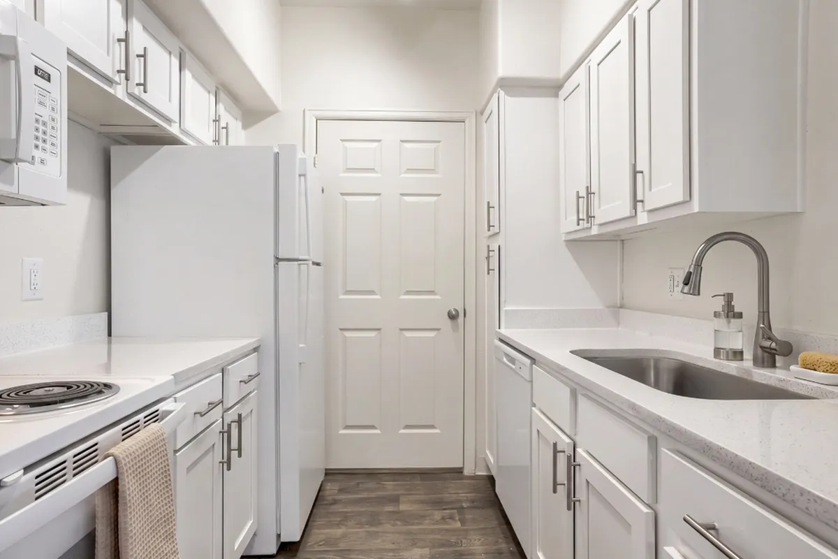 Bright and modern galley kitchen featuring sleek white cabinetry, stainless steel fixtures, and elegant countertops.