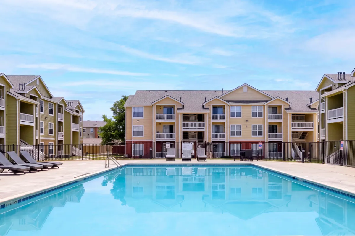 Inviting apartment complex with modern architecture featuring a refreshing outdoor pool and cozy lounge area.